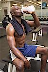 Sporty shirtless muscular man drinking protein in gym