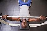 High angle view of a determined muscular man lifting barbell in gym