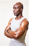 Serious muscular man with arms crossed looking away over white background