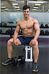 Portrait of a shirtless muscular man sitting in the gym