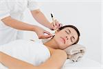 Close up of a beautiful young woman receiving ear candle treatment at spa center