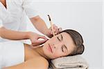 Side view of a beautiful young woman receiving ear candle treatment at spa center