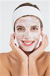 Close-up of an attractive woman having white cream on her face at spa center
