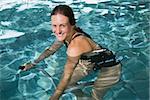 Fit brunette using underwater exercise bike in swimming pool at the leisure centre