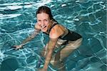 Fit happy brunette using underwater exercise bike in swimming pool at the leisure centre