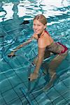 Fit happy blonde using underwater exercise bike in swimming pool at the leisure centre