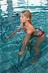 Fit blonde using underwater exercise bike in swimming pool at the leisure centre