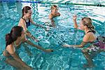 Fitness class doing aqua aerobics on exercise bikes in swimming pool at the leisure centre