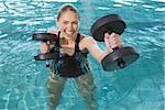 Fit blonde working out with foam dumbbells in swimming pool at the leisure centre