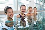 Female fitness class smiling at camera in swimming pool at the leisure centre