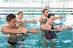 Happy fitness class doing aqua aerobics in swimming pool at the leisure centre