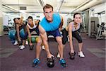 Muscular instructor leading kettlebell class at the gym