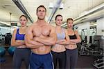 Serious fitness class posing together at the gym