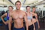 Smiling fitness class posing together at the gym