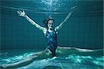 Athletic swimmer posing for camera and smiling underwater in the swimming pool at the leisure centre