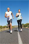 Fit couple running on the open road together on a sunny day