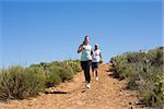 Fit couple running up mountain trail on a sunny day