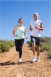 Fit couple running down mountain trail on a sunny day