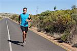 Athletic man jogging on open road on a sunny day