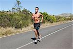 Shirtless man jogging on open road  on a sunny day