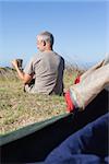 Happy camper sitting outside his tent holding mug on a sunny day