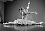 Graceful ballerina sitting with legs stretched out in the ballet studio