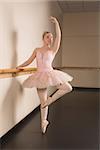 Beautiful ballerina standing en pointe holding barre in the dance studio