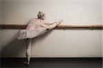 Beautiful ballerina warming up with the barre in the dance studio