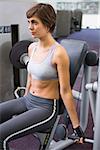 Healthy brunette using weights machine for arms at the gym