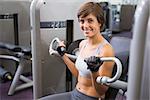 Healthy happy brunette using weights machine for arms at the gym