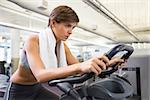 Fit focused brunette working out on the exercise bike at the gym