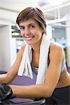 Fit smiling woman working out on the exercise bike at the gym