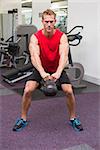 Strong man lifting heavy kettlebell at the gym