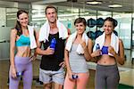 Fit man and women smiling at camera in studio at the gym