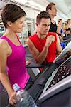 Trainer talking to his client on the treadmill at the gym