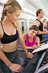 Trainer talking to her client on the treadmill at the gym