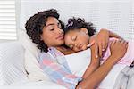 Cute daughter sleeping with mother on the sofa at home in the living room