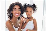 Pretty mother teaching her daughter about makeup  at home in the bathroom