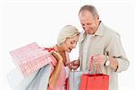 Smiling mature couple holding shopping bags on white background
