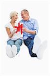 Happy mature couple holding a gift on white background