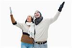 Attractive young couple in warm clothes with arms up on white background