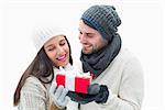 Attractive young couple in warm clothes holding gift on white background