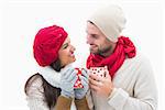 Attractive young couple in warm clothes holding mugs on white background