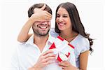 Pretty brunette surprising boyfriend with a gift on white background