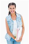 Pretty student smiling and holding notepads on white background