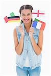 Pretty brunette holding various european flags on white background