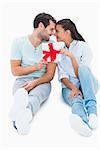 Cute couple sitting holding a gift on white background