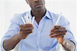 Businessman deciding between electronic or normal cigarettes in his office