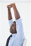 Relaxed businessman stretching in his chair in his office