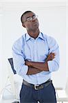 Thoughtful businessman standing with arms crossed in his office